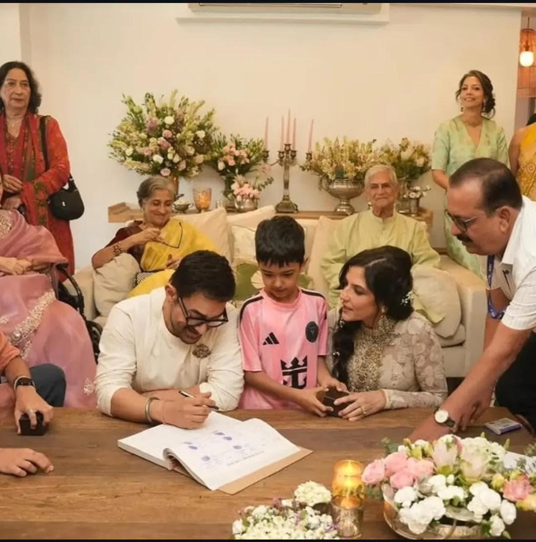 Aamir Khan signs a wedding register while seated beside his bride, with family members gathered around during an intimate wedding ceremony.