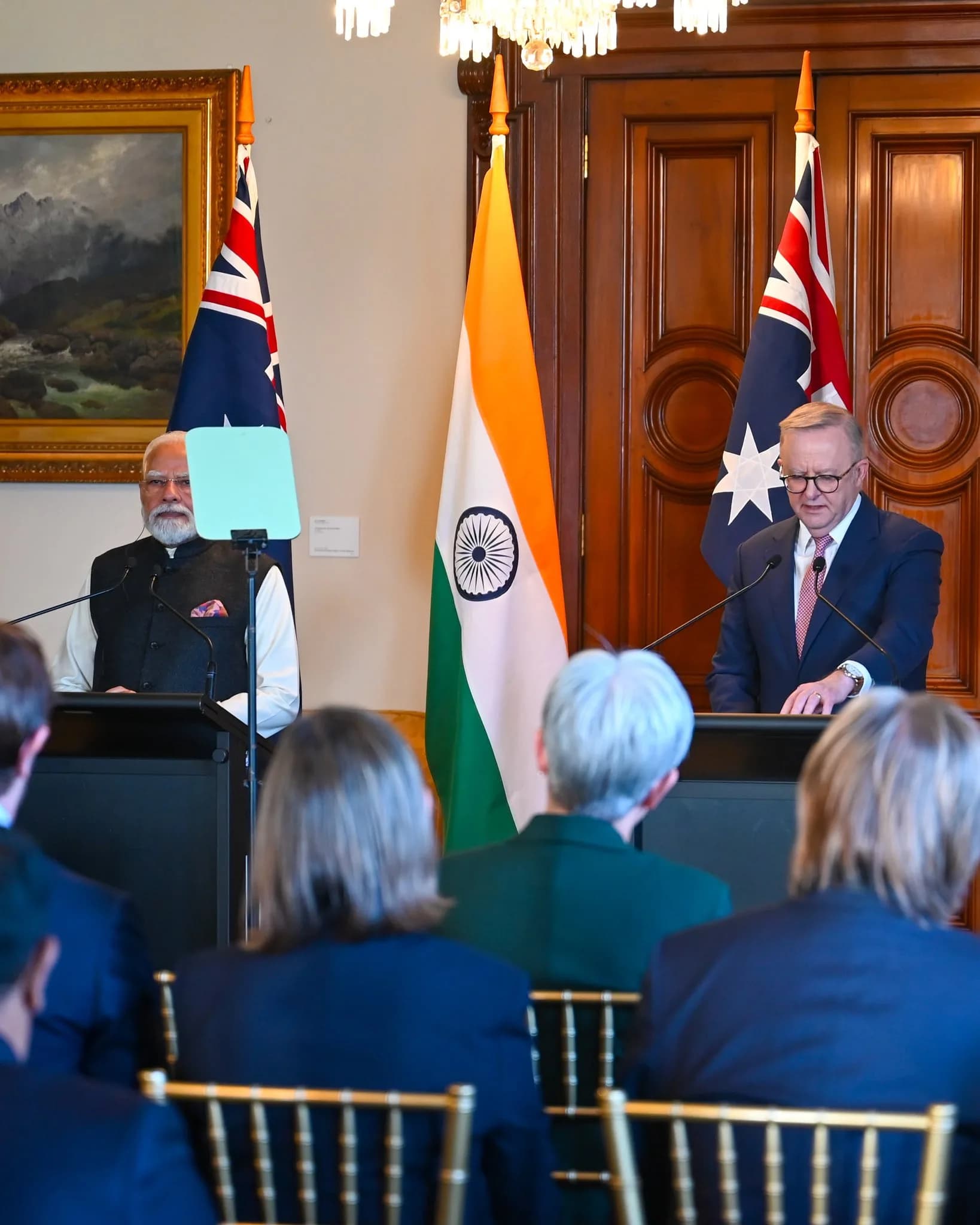 Prime Minister Narendra Modi and Australian Prime Minister Anthony Albanese address a joint event during Modi's Australia visit, with the Indian and Australian flags displayed behind them.