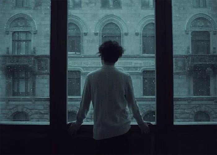 A person sitting quietly by a window with eyes closed, reflecting peacefully as a symbol of letting go of overthinking.